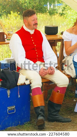 MOSCOW REGION - SEPTEMBER 07, 2014: Portrait of a man dressed in historical costume, he sits on a bench. He is a reenactor, he participates in Borodino battle historical reenactment.