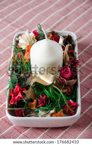 White decorative candle with dried flowers.