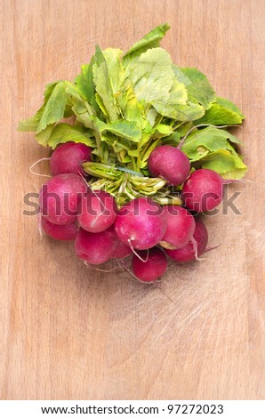 Natural fresh red radish recently picked from garden on a used wood cutting board.