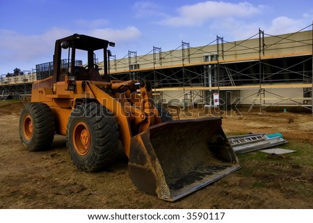 Earth mover in front of scaffolding for a new parking lot under construction