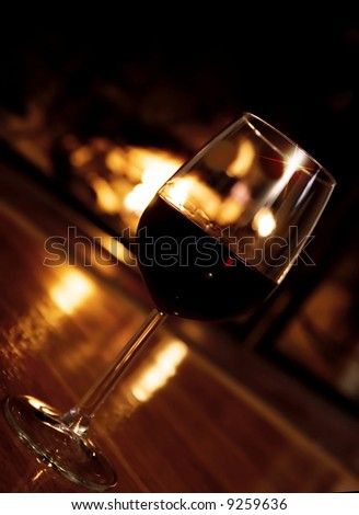 Glass of wine in front of the fireplace.  Selective focus, golden glow from the fire.