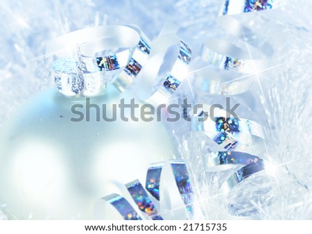 Silver bauble with sparkling ribbon on snowy tinsel - cold winter blue toning