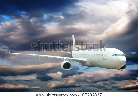 Plane is flying in the sky among light and dark clouds.