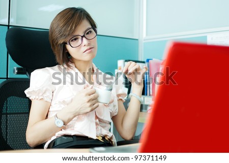 Portrait of a woman at the office for a portable computer with a cup of coffee