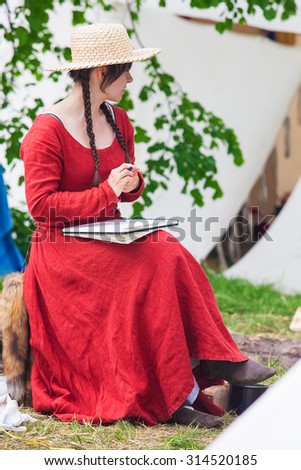 Prague, Czech Republic - May 05, 2015: Young beautiful women in long medieval dresses sitting in medieval knights camp.