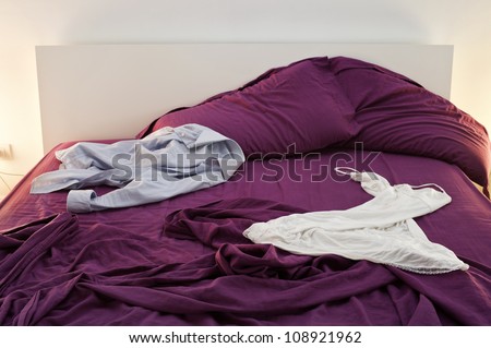 man and woman\'s clothes on undone bed