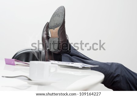 manager with feet on desk and cup of coffee