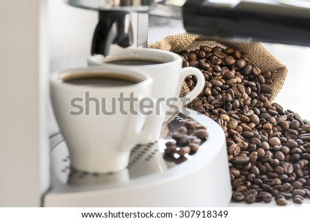coffee machine with two coffee cups and coffee beans, focus on coffee beans
