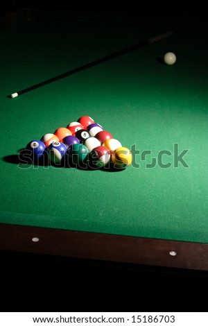 Racked pool balls with the cue stick and cue ball in the background.