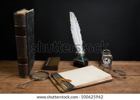 Quill and inkwell, antique notebook, book, magnifying glass, vintage clock, spectacles on oak wooden table