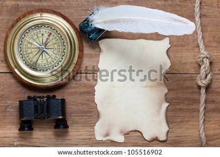 Compass, paper, quill and inkwell, binoculars, rope knot on old wood