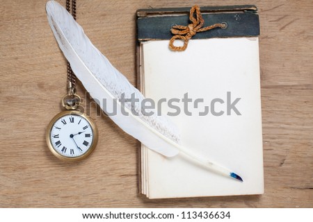Old notebook, quill and pocket watch on wood