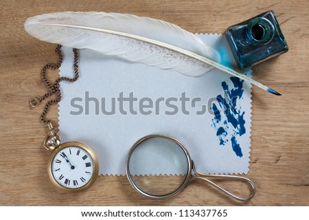 Retro pocket watch, quill, inkwell, paper blank and magnifying glass on wood