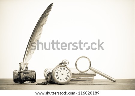 Pocket watch, quill pen and inkwell, book, magnifying glass on the table