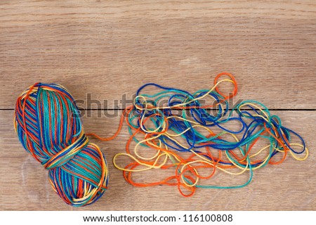 Knitting color thread hank and tangle on wooden texture background