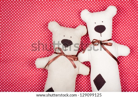 Handmade pair of bears on red textile texture background
