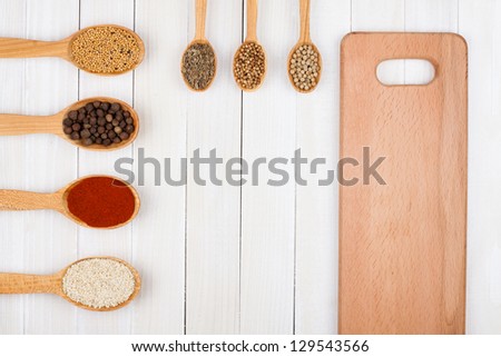 Spices in wooden spoons on white wood background