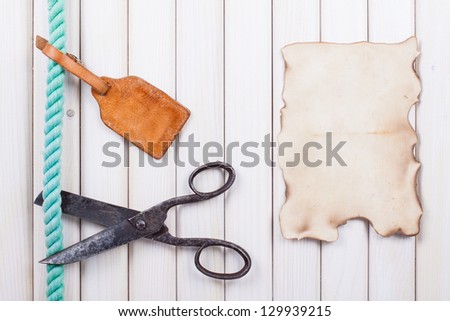 Old scissors cutting rope, poster, tag on wooden background