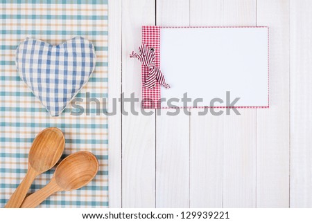 Notebook, tablecloth, heart, spoons on white wood table
