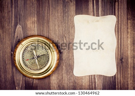 Big vintage compass and paper on wooden texture background