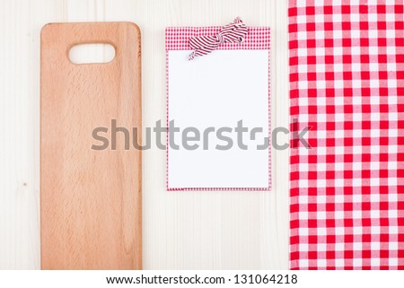 Recipe notebook, red and white tablecloth, plank on wood background