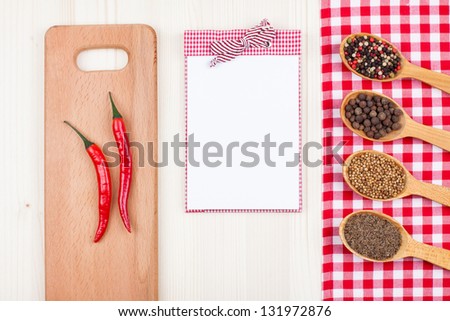 Recipe cook book, chili, spices, red and white tablecloth on wood background