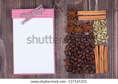 Recipe or menu note book, coffee, cinnamon, star anise, cardamom on wood background