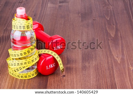 Fitness sport dumbbells, measure tape, bottle of water on wood floor