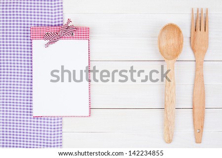 Tablecloth, recipe cook book, spoon, fork on white wood background