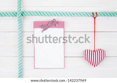 Notebook and heart hang on white wood wall background