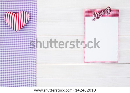 Notebook, tablecloth, heart on white wood background