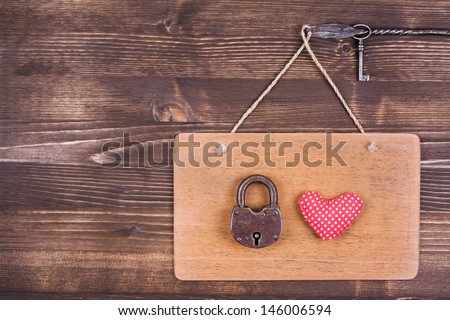 Heart, key and lock on signboard hanging on vintage wood background