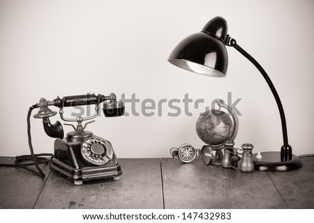 Vintage telephone, retro table lamp, compass, binoculars on table still life