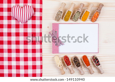 Spices in scoops, recipe cook book, tablecloth, heart on wood background