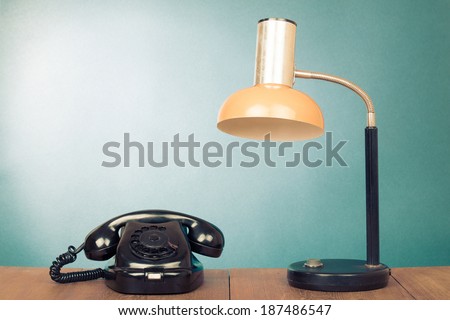 Retro rotary telephone and desk lamp on table
