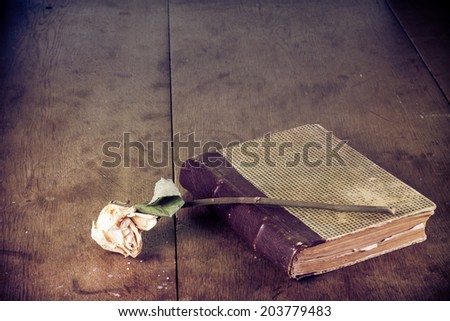 Old book and dried flower on grunge vintage wooden table