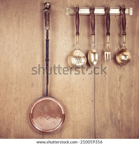 Vintage old kitchen tools hangs on oak wood wall background