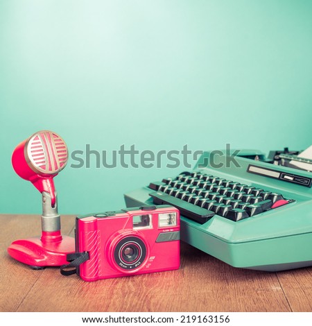 Retro journalism equipments: photo camera, microphone old typewriter on desk front mint green background