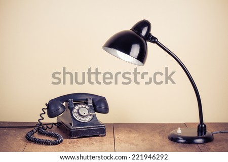 Old retro telephone and desk lamp on wooden table