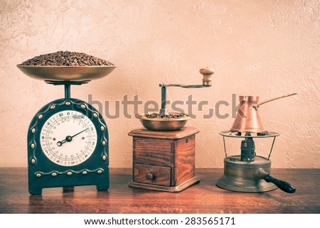Retro weight measurement balance with coffee beans, coffee grinder, coffee pot on kerosene cooking stove. Vintage instagram style filtered photo