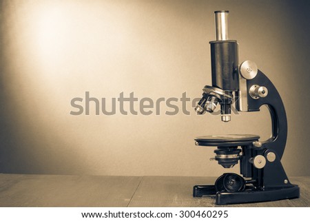 Retro old microscope on table. Vintage style sepia photo