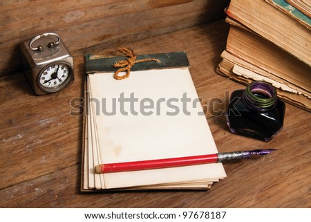 Antique notebook, vintage clock, ink pen and inkwell, old books on wood background