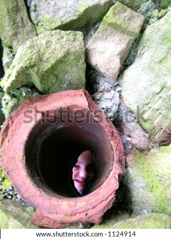 Peek a Boo  Description: Little girl peeks through a drain pipe