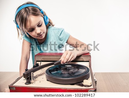 Testing the needle on LP record player vintage musical sound meets new age ears of little blonde girl child