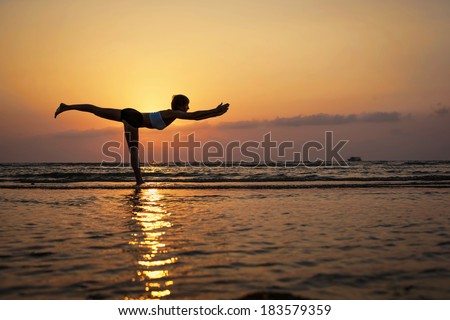 Yoga virabhadrasana III, pose by woman in silhouette with sunset sky background. Free space for text