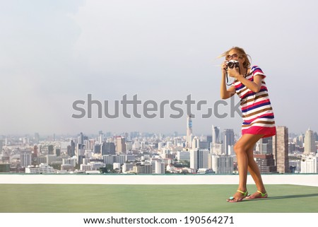 Beautiful woman photographer on the roof of a skyscraper in travel