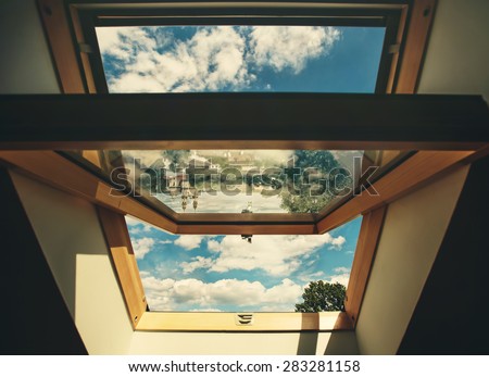 Open roof window skylight with old European city reflection, the chapel and cloud sky