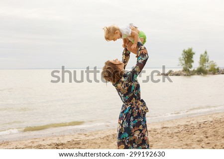 Young Mother and her Little Daughter Baby Outdoor Playing on the Beach near Sea. Family Love Concept