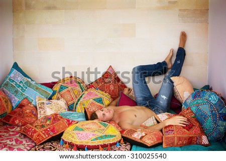 Man in Luxury interior Relax on big sofa with Colored Pillows