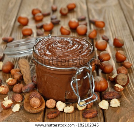 Chocolate paste in a glass jar on a brown background